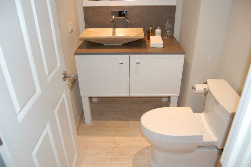 A bathroom with a toilet , sink and cabinets