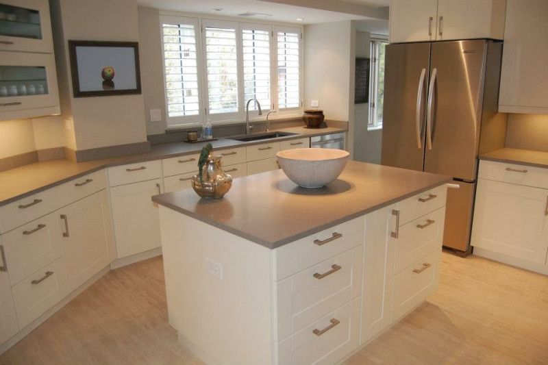A kitchen with white cabinets and a stainless steel refrigerator