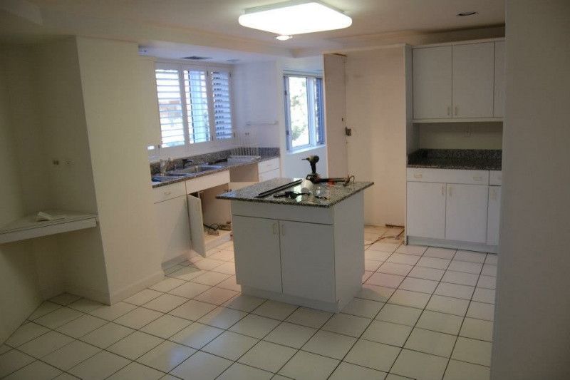 An empty kitchen with white cabinets and a large island