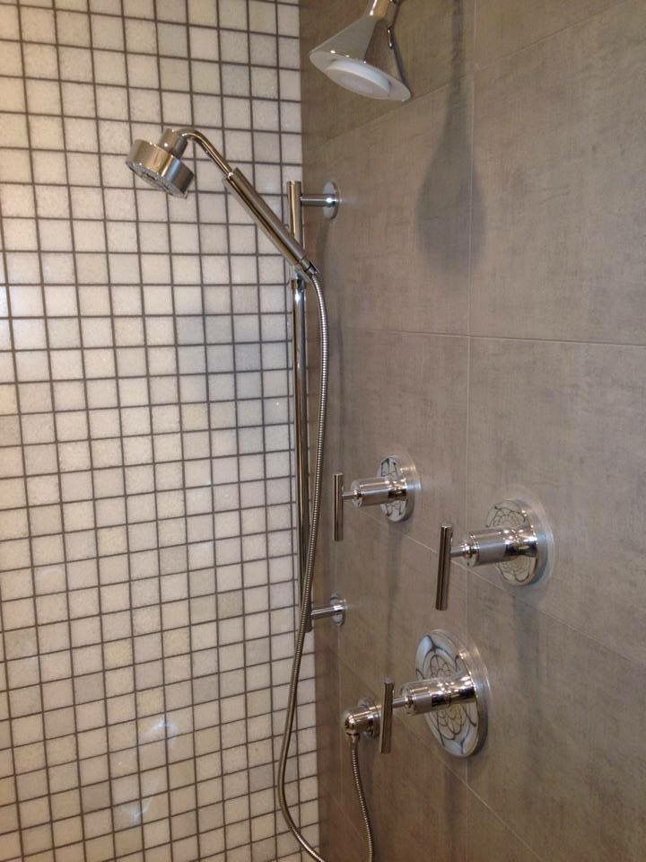 A shower with three shower heads and three faucets