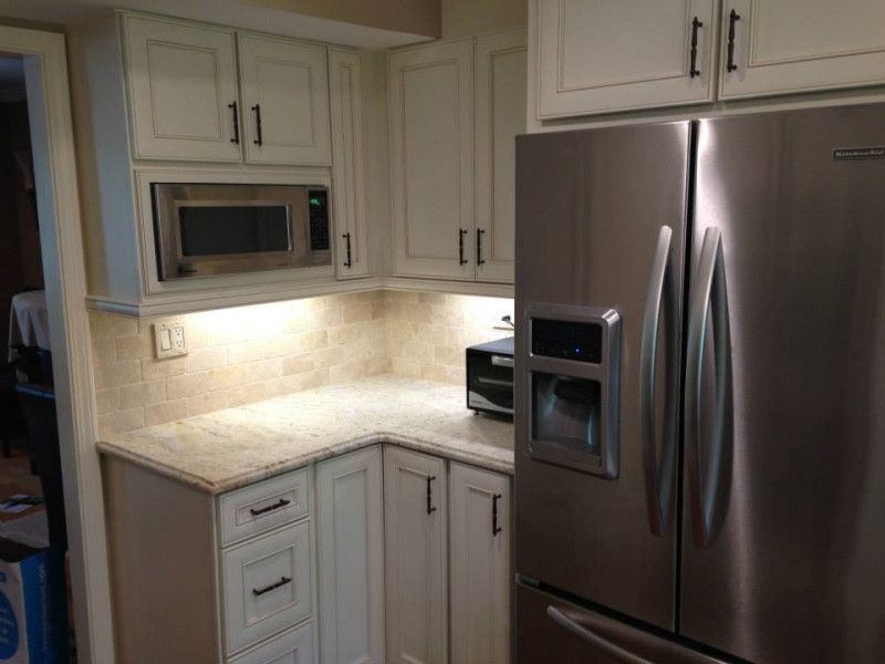 A kitchen with white cabinets and a stainless steel refrigerator
