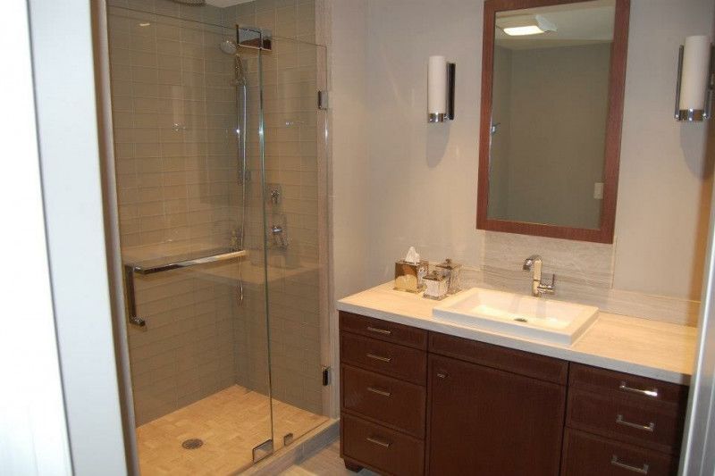 A bathroom with a sink , mirror and walk in shower.