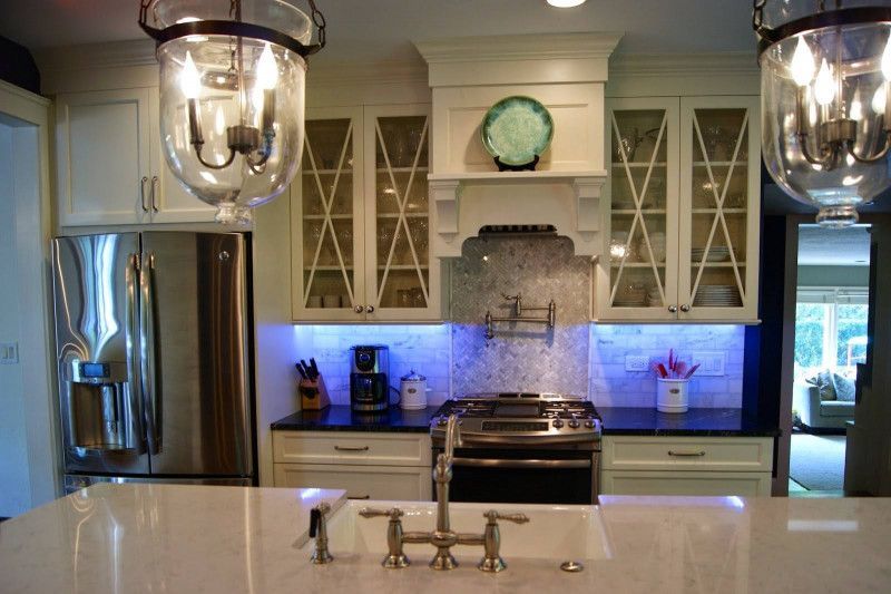 A kitchen with white cabinets , stainless steel appliances , a sink and a refrigerator.
