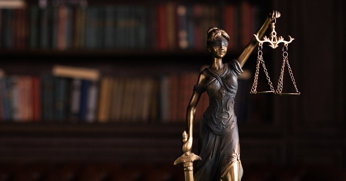 Statue of Lady Justice holding scales and sword, set in front of a bookcase.