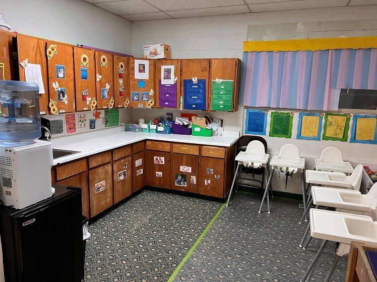 A kitchen with wooden cabinets , a sink , and high chairs.