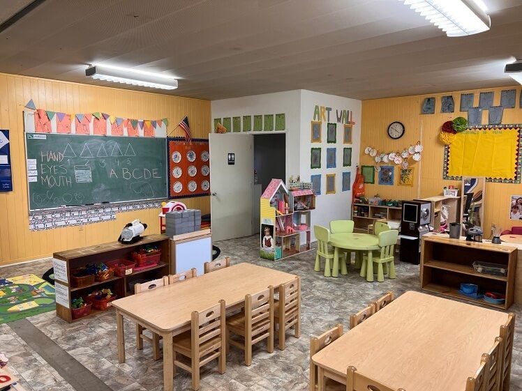 A classroom with tables and chairs and a chalkboard.