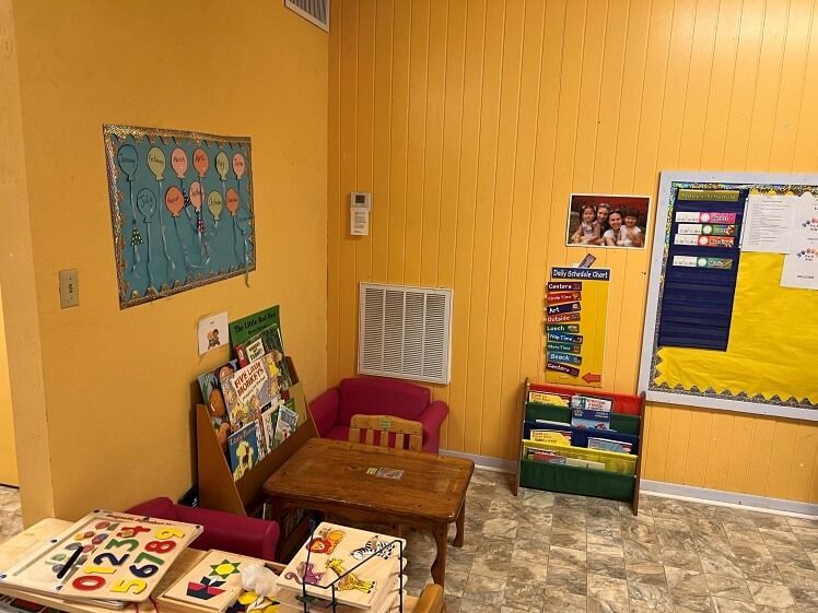 A room with a table , chairs , bookshelves and a bulletin board.