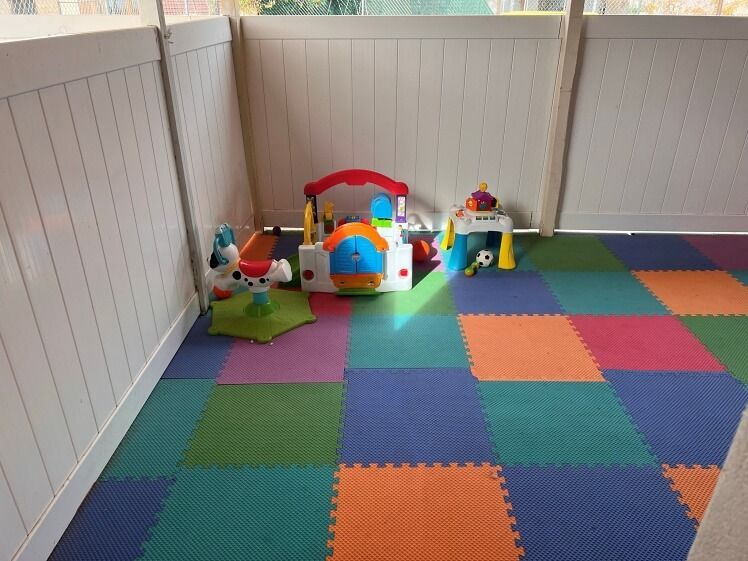 A colorful play area with toys and a white fence