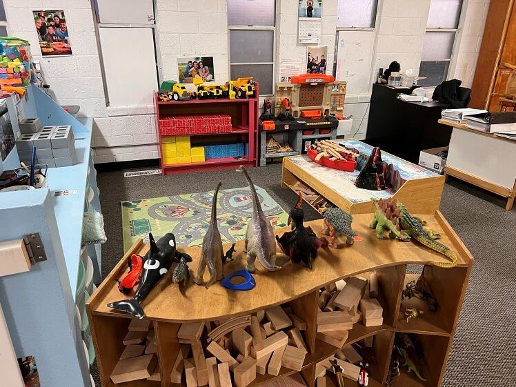 A room filled with lots of toys and a table with dinosaurs on it.