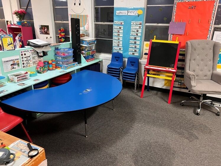 A classroom with a blue table and chairs
