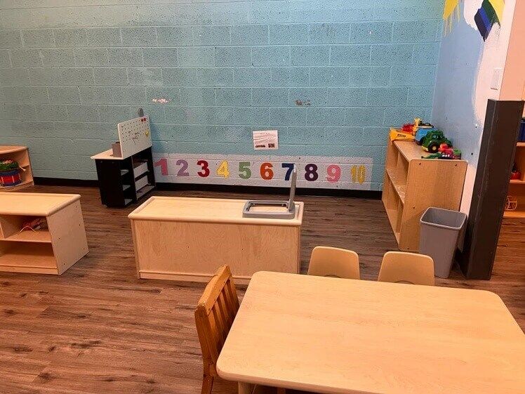 A room with a table and chairs and a brick wall with numbers on it.