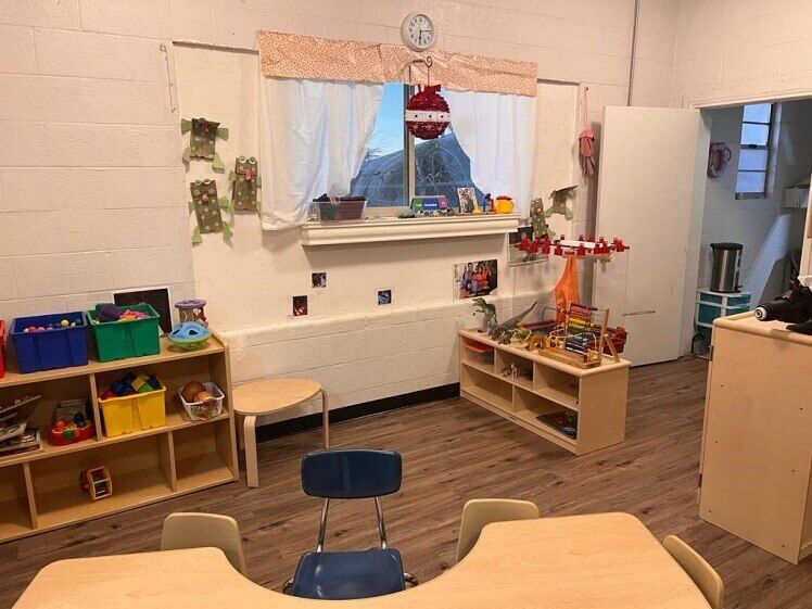 A classroom with tables , chairs , shelves and toys.