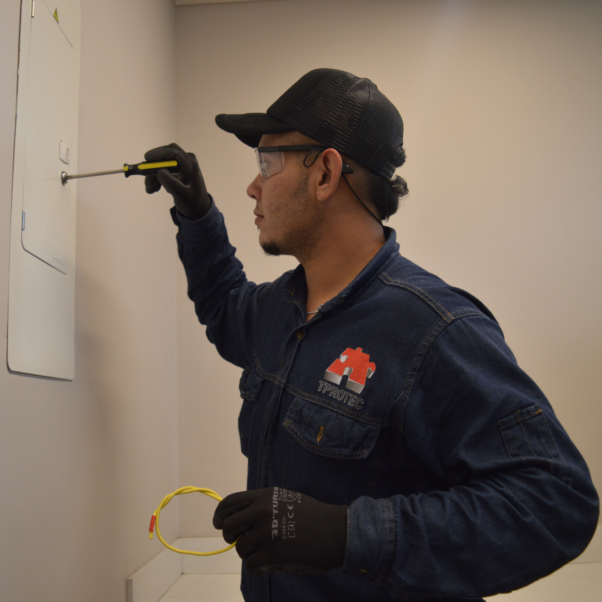 Un hombre con una camisa vaquera sostiene un destornillador.