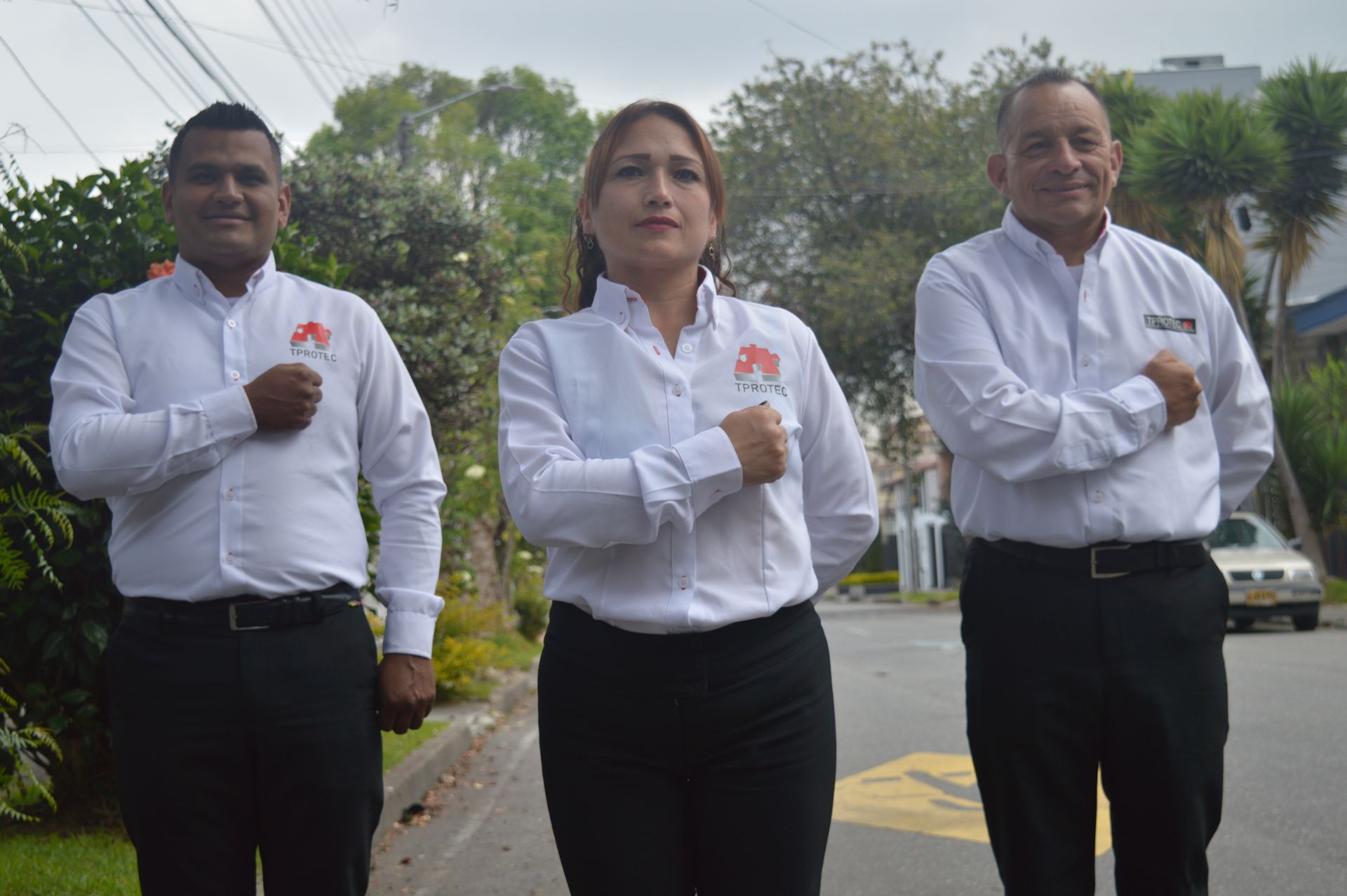 Tres personas están paradas una al lado de la otra al costado de la carretera.