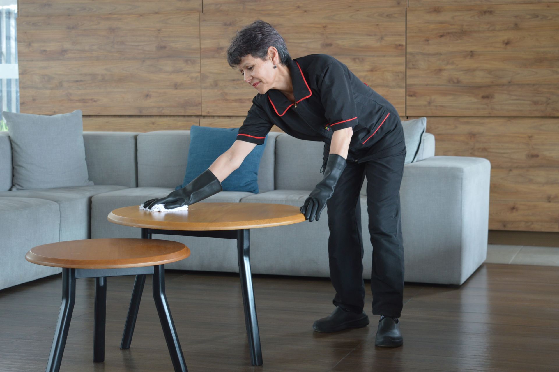 Una mujer está limpiando una mesa en una sala de estar.