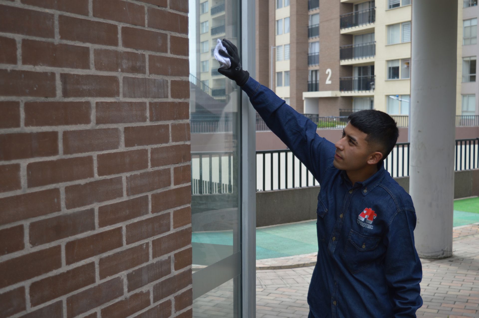Un hombre con una camisa azul está limpiando una pared de ladrillos con una esponja.
