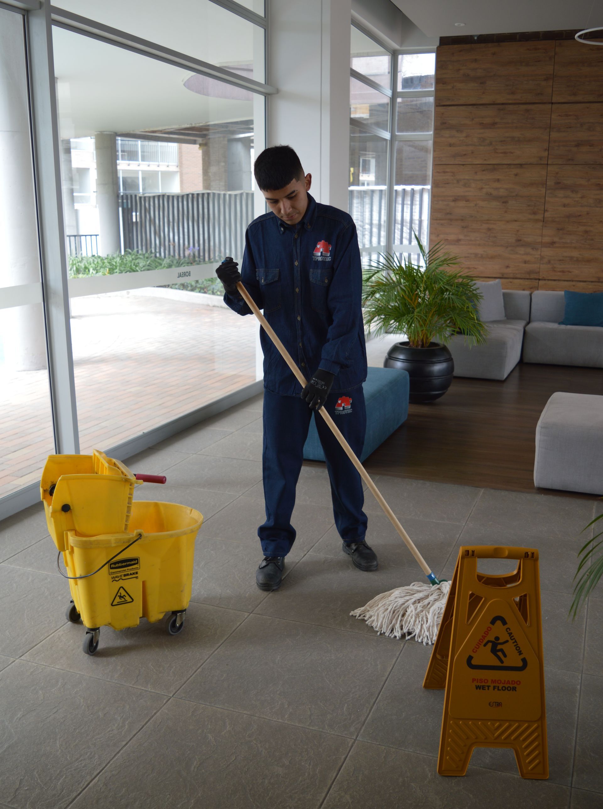 Un hombre está limpiando el suelo con un trapeador y un balde.