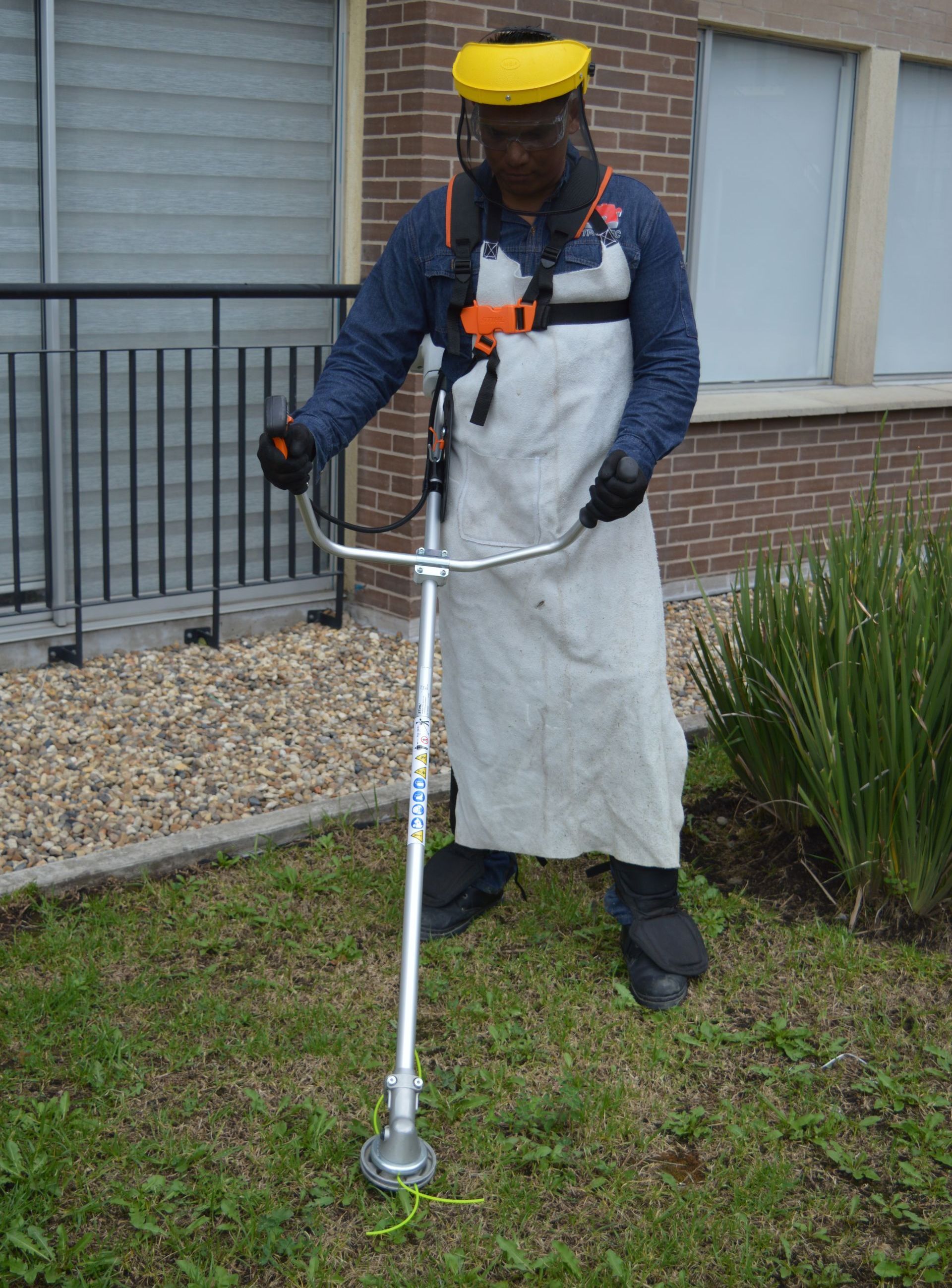 Un hombre está parado en el césped usando una cortadora de césped.
