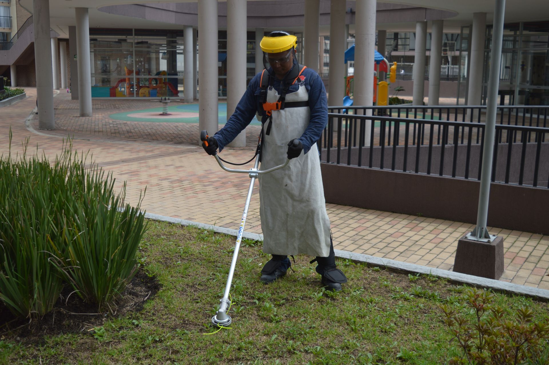 Un hombre está cortando el césped con una cortadora de césped en un parque.