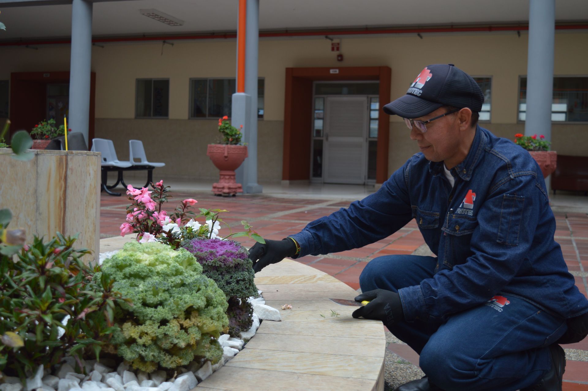 Un hombre se arrodilla y planta flores en un jardín.