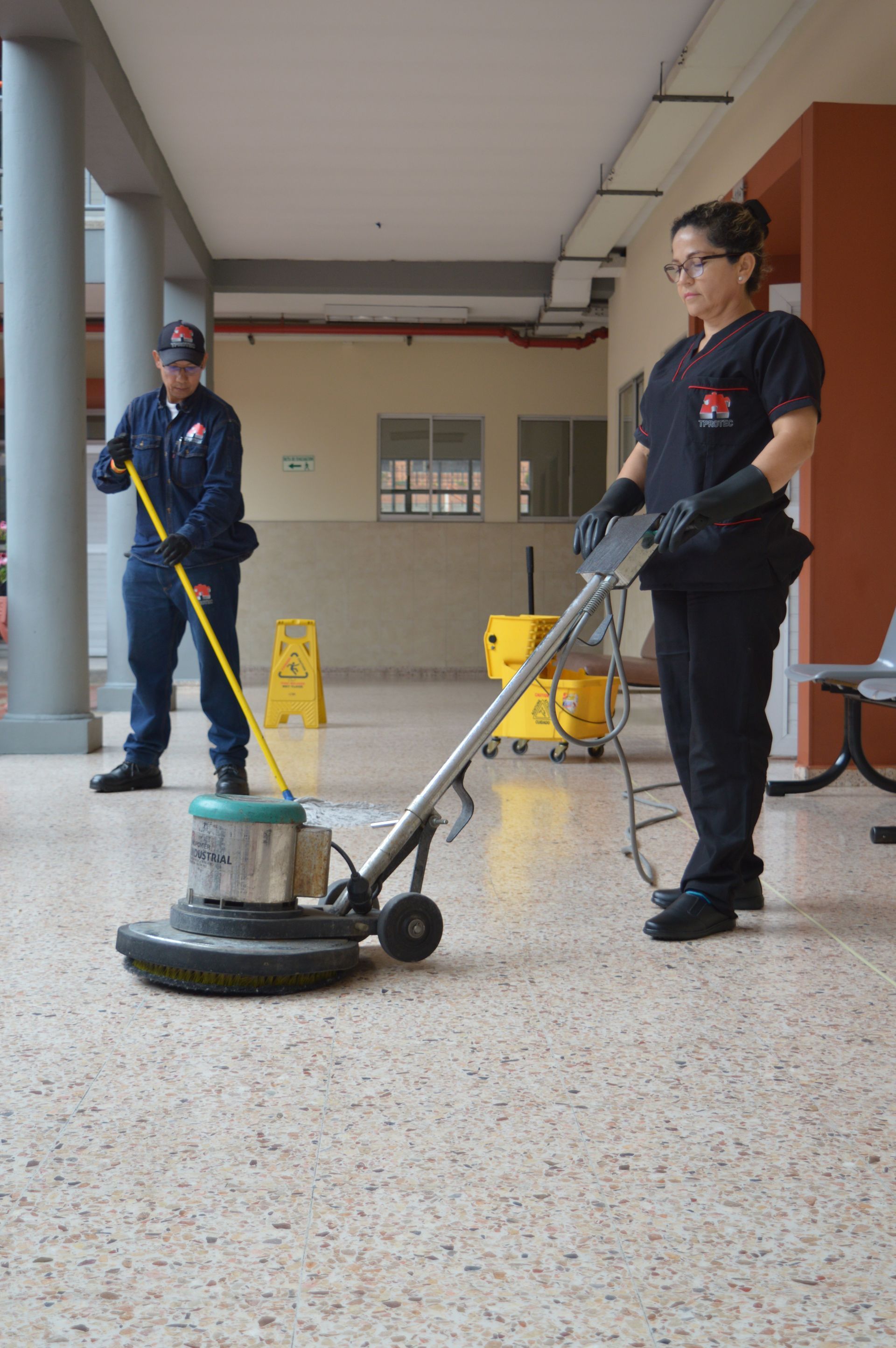 Un hombre y una mujer están limpiando un piso con una máquina.