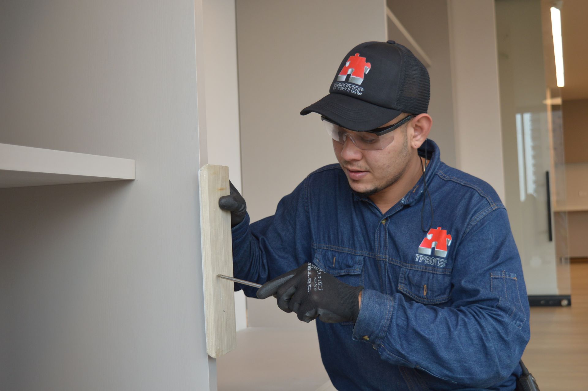 Un hombre está trabajando en una pared con un destornillador.