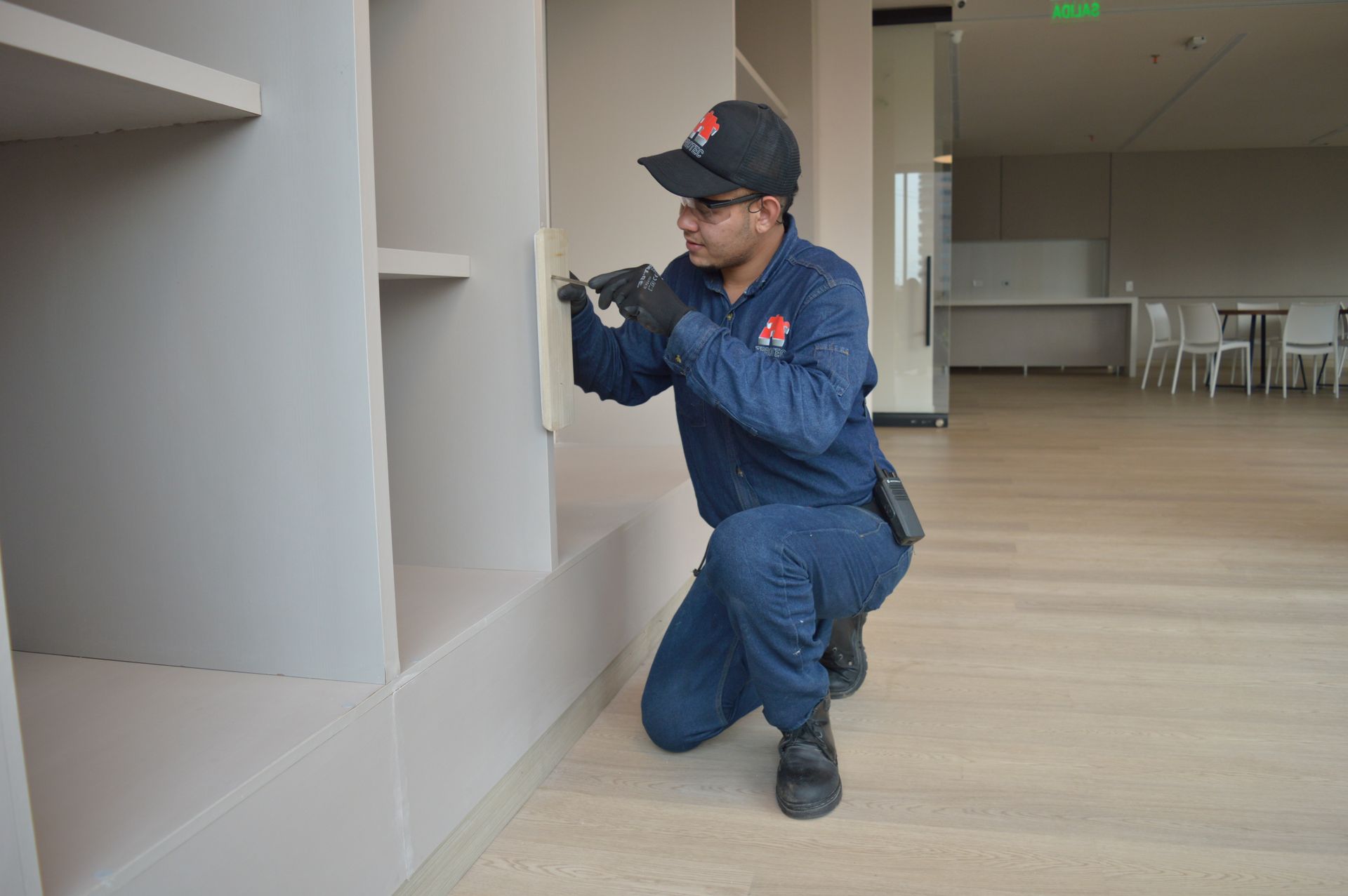 Un hombre está arrodillado en una habitación mirando un estante.