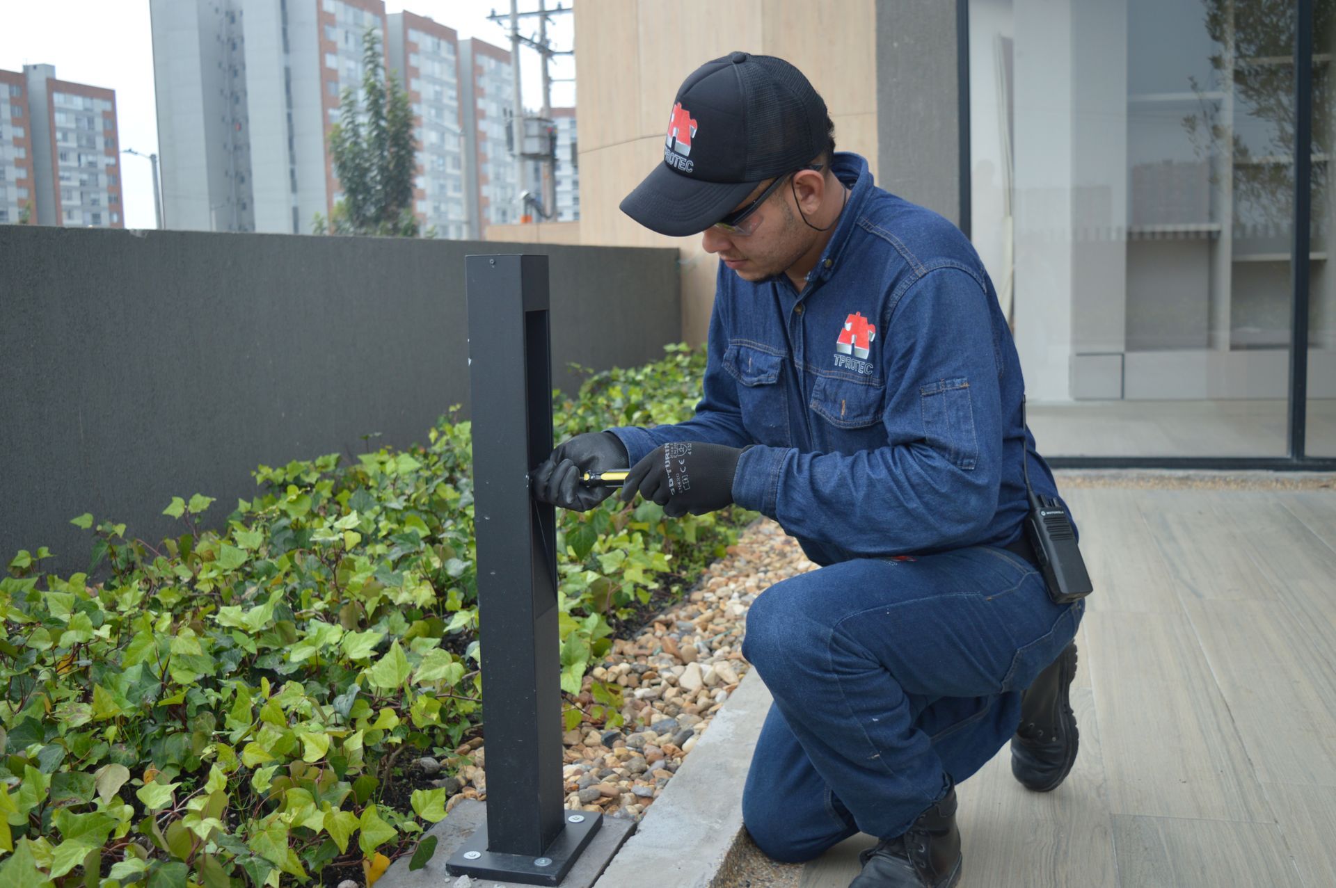 Un hombre está arrodillado y trabajando en un poste.