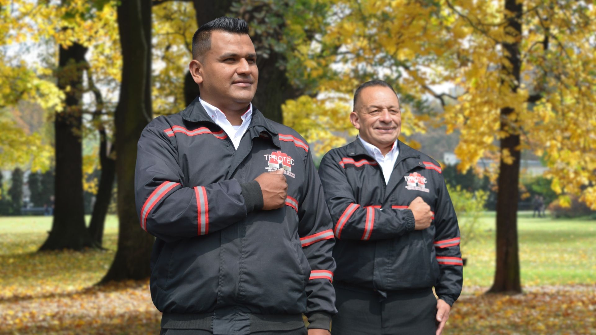 Dos hombres están parados en un parque con las manos en el pecho.
