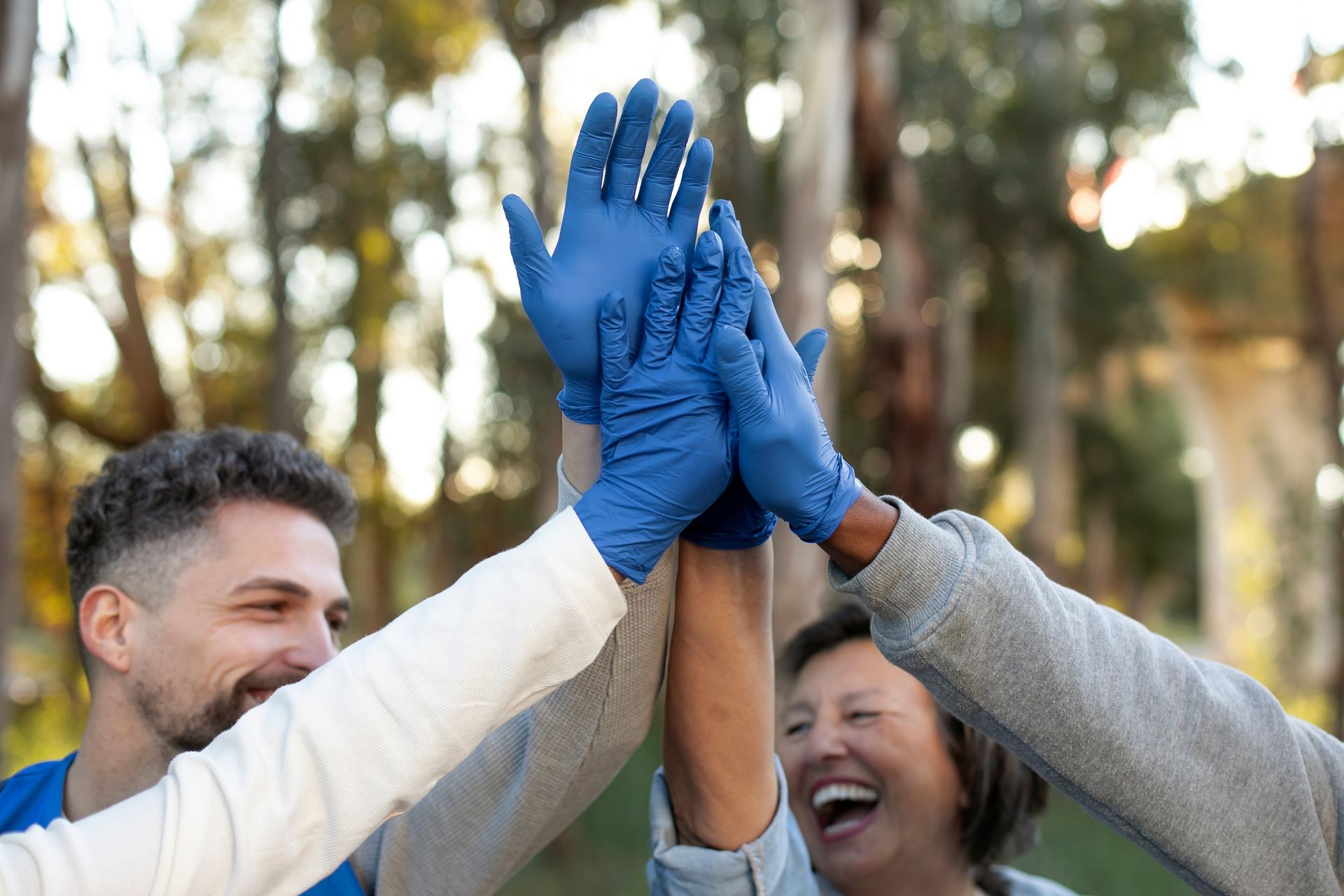 Un grupo de personas que llevan guantes azules se chocan los cinco.