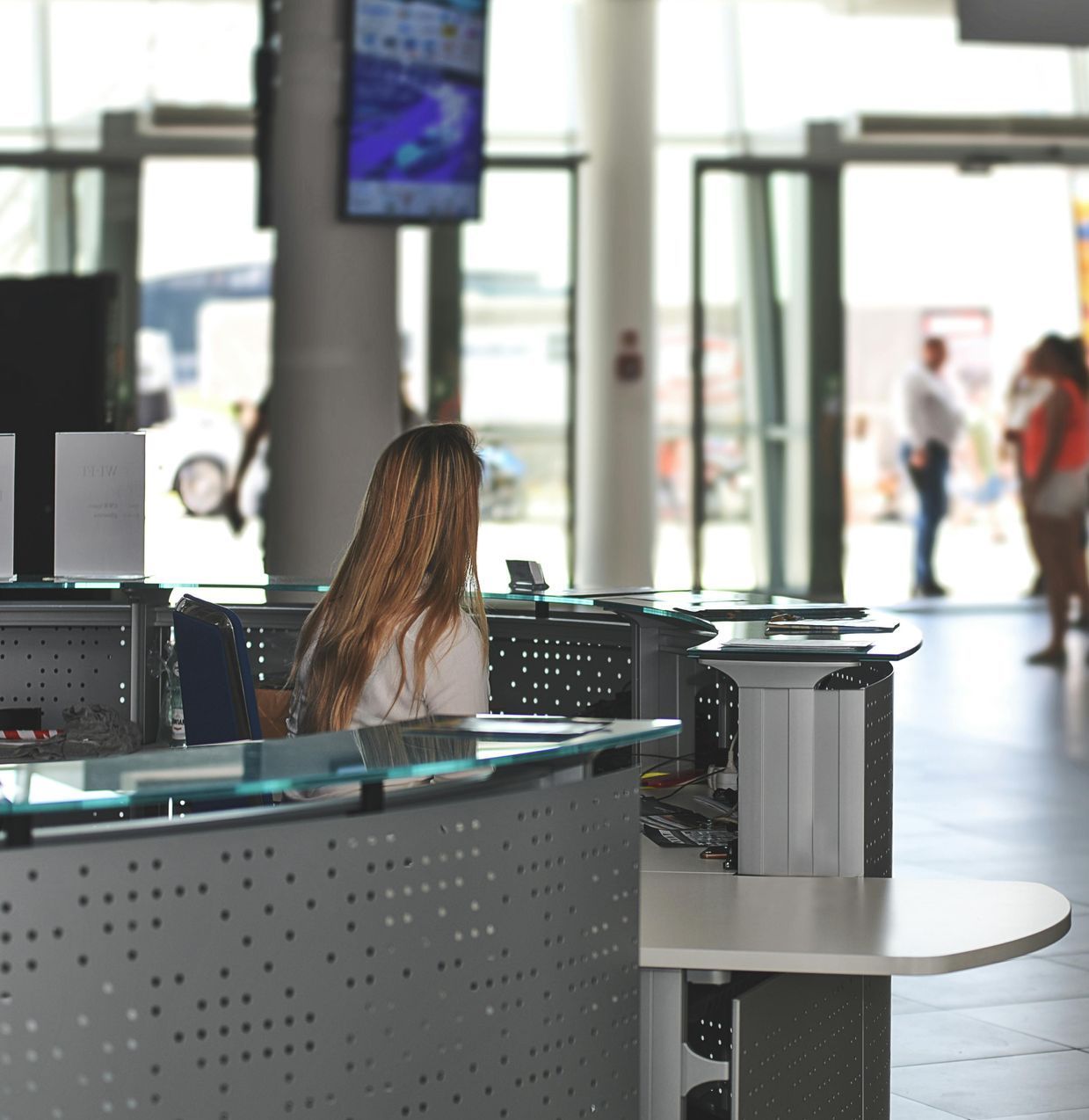 Una mujer se sienta en un escritorio frente a un televisor.
