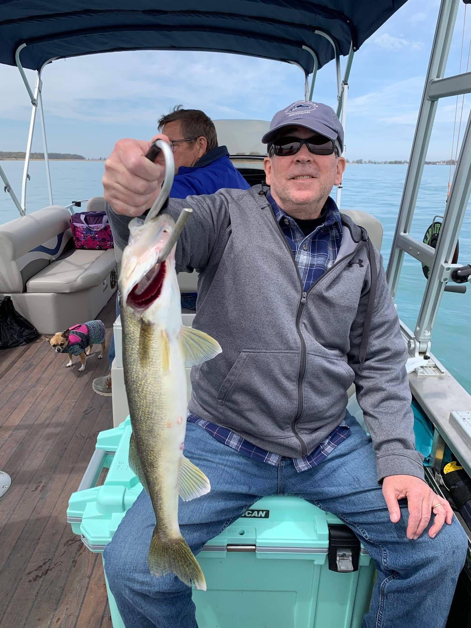 A man is sitting on a boat holding a fish in his hand.