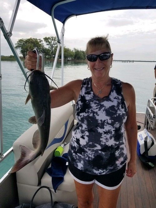 A woman is holding a large fish on a boat.