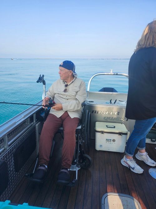 A man in a wheelchair is fishing on a boat.