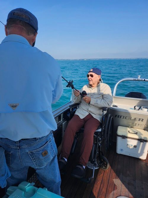 A man in a wheelchair is fishing on a boat.