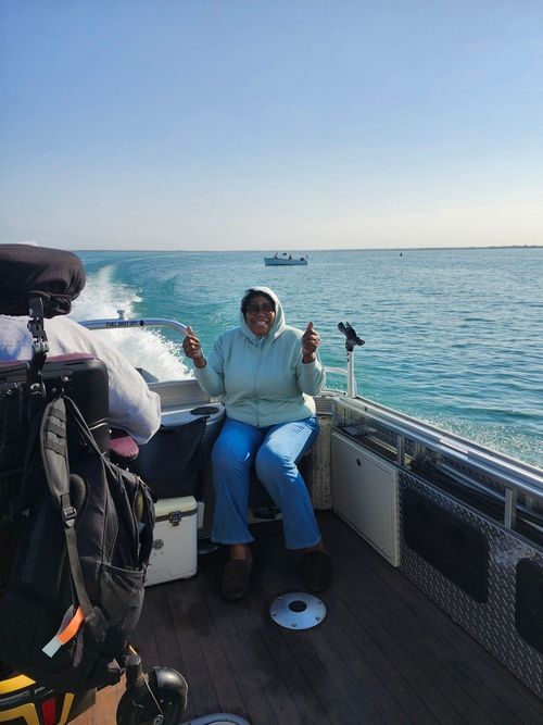A woman is sitting on a boat in the ocean holding a fishing rod.