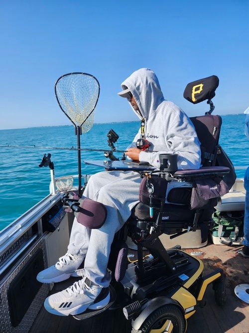 A man in a wheelchair is fishing on a boat