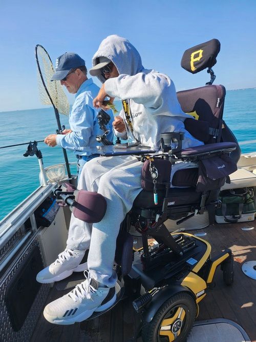 A man in a wheelchair is fishing on a boat.