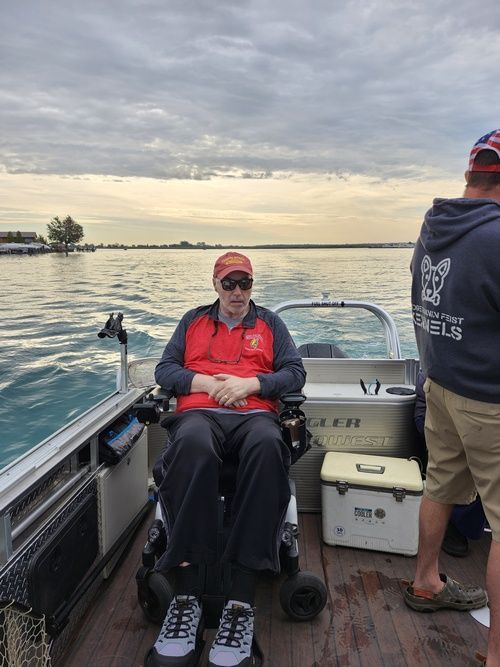 A man in a wheelchair is sitting on the deck of a boat.
