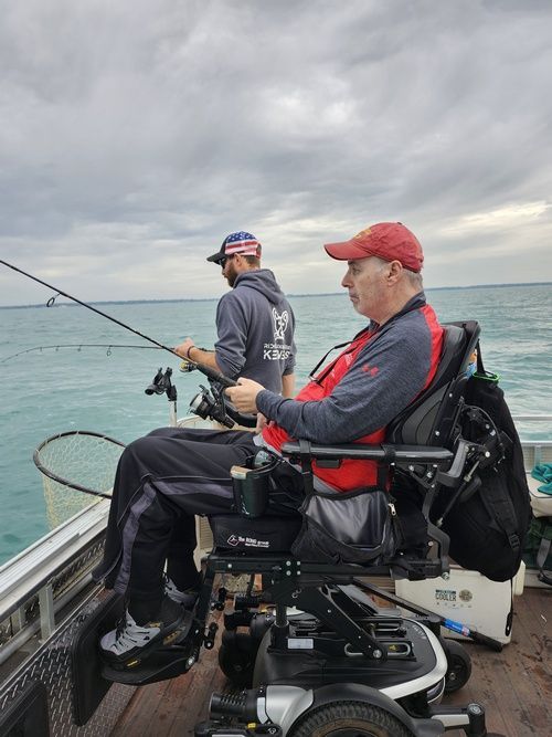 A man in a wheelchair is fishing on a boat.