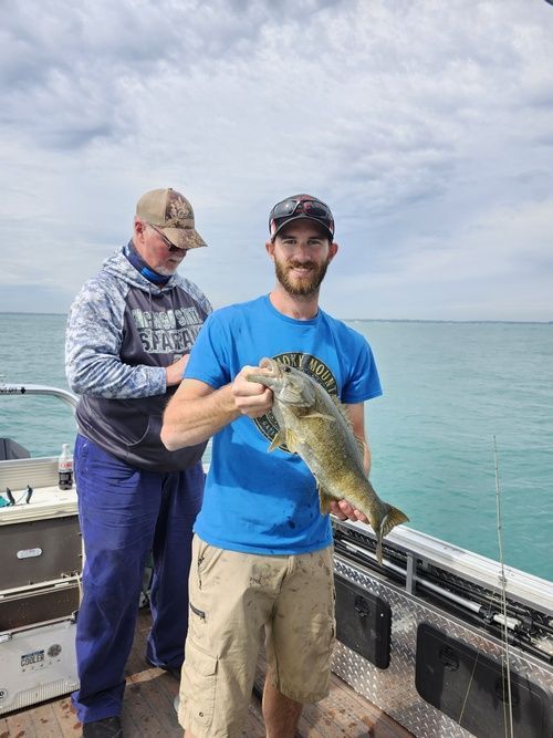 Two men are standing on a boat holding a fish.