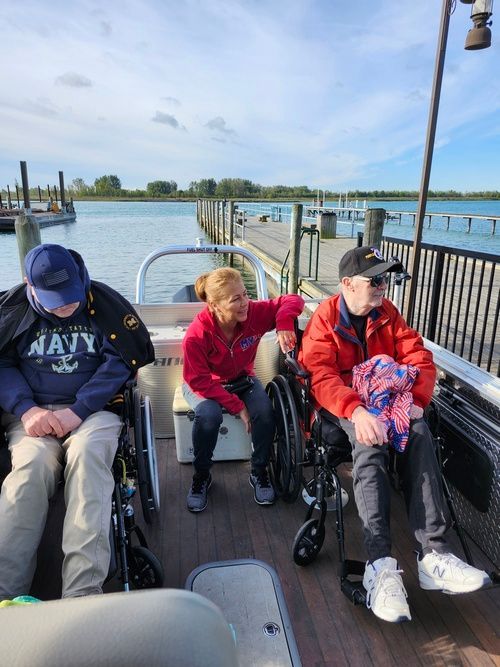 A group of people in wheelchairs are sitting on a boat.
