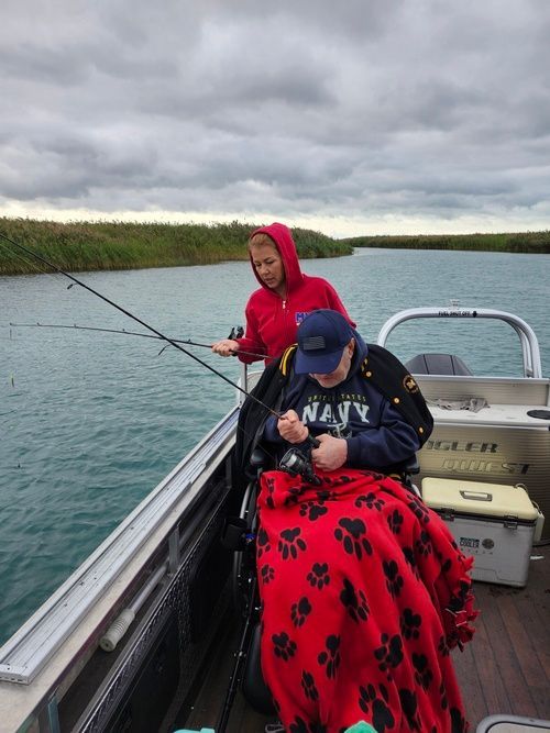 A man in a navy shirt is fishing on a boat.