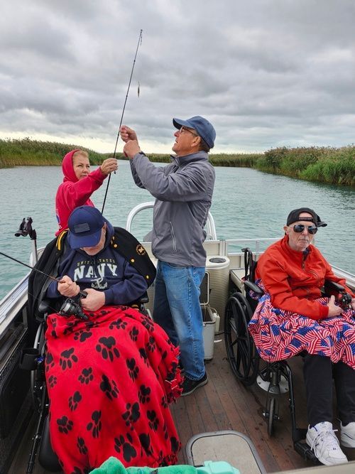 A group of people in wheelchairs are fishing on a boat.