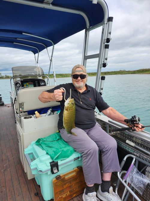 A man is sitting on a boat holding a fish.