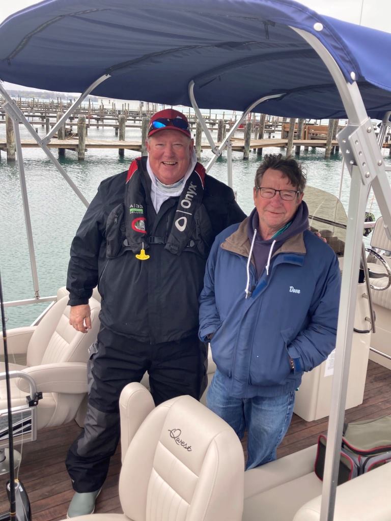 Two men are standing next to each other on a pontoon boat.