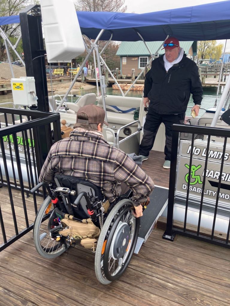 A man in a wheelchair is getting on a boat.