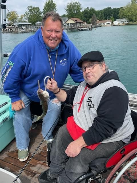 A man in a wheelchair is fishing with another man