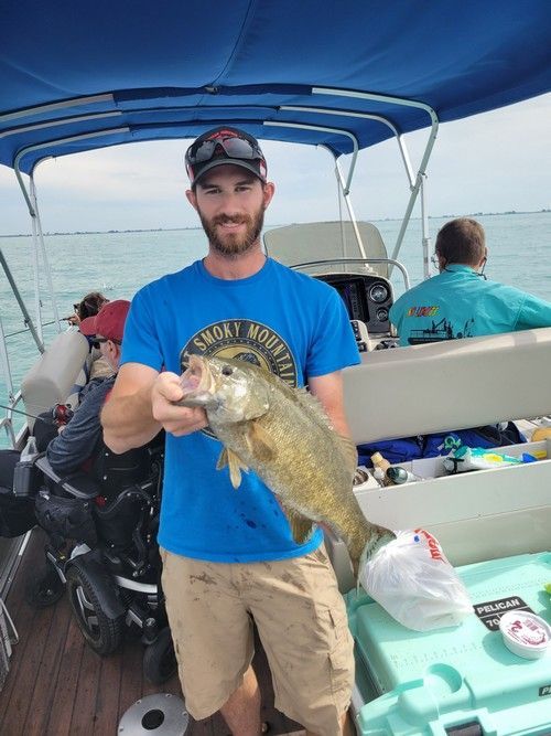 A man in a blue shirt is holding a fish on a boat.
