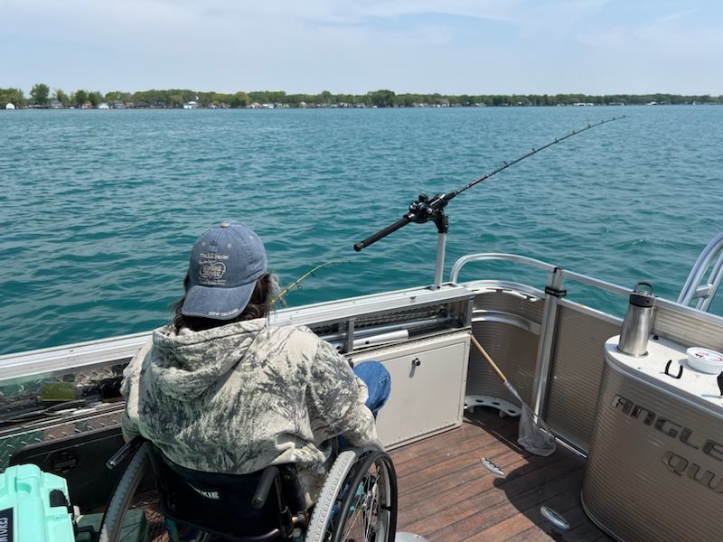 A man in a wheelchair is fishing on a boat.